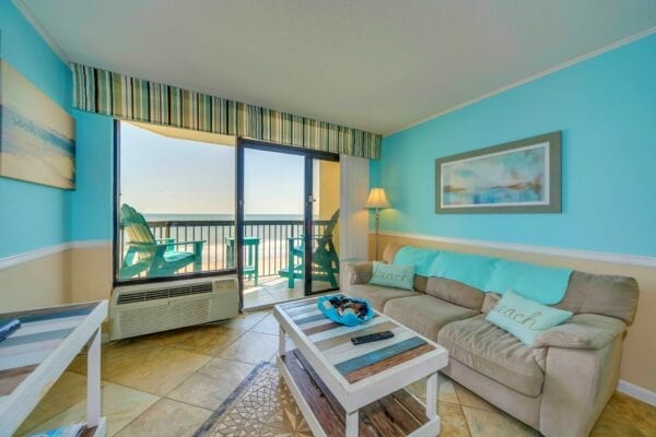 A brown sofa next to the Pinnacle Oceanfront Tower 452 balcony door