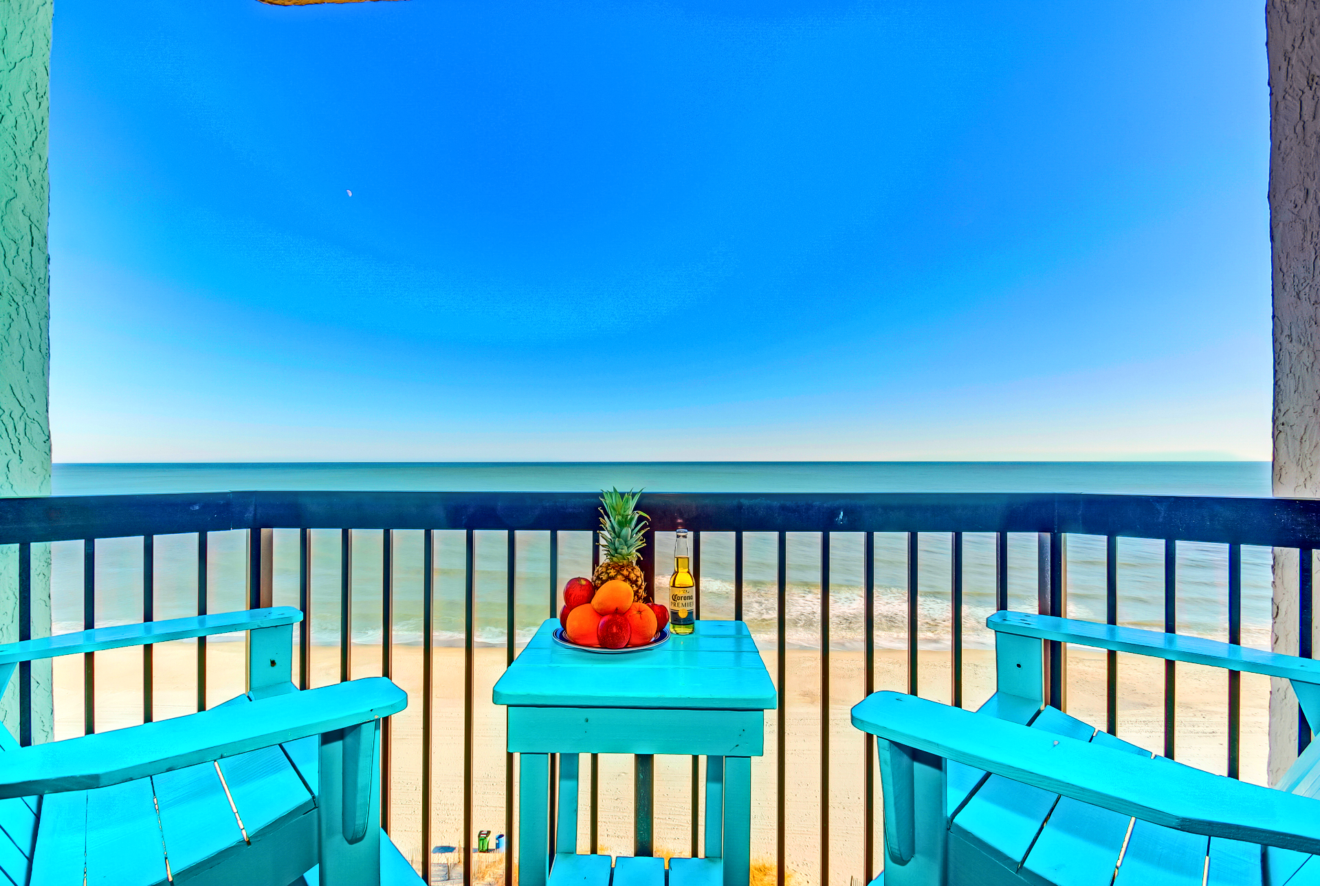 A fruit bowl and drink on a teal balcony table
